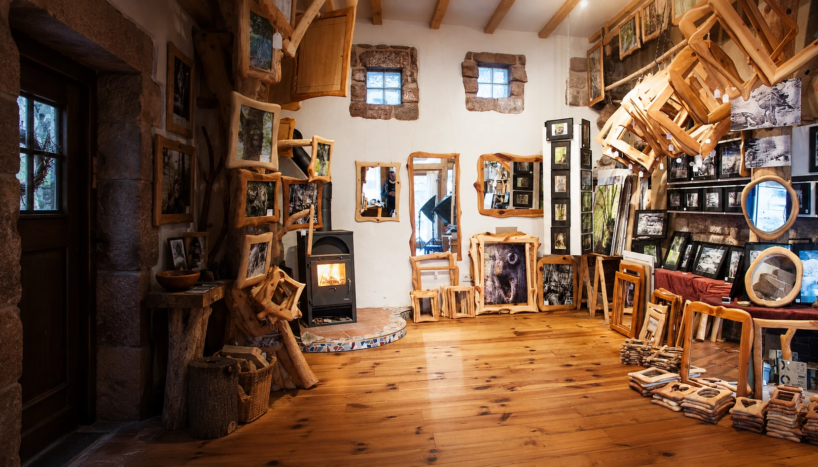 Die Galerie mit Sandsteinfenstern, Holzofen und Achims Fotografien, Rahmen und Spiegeln.